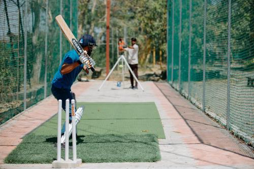 a man holding a bat in a batting cage at Daksh Eden Greenz -A Luxury Resort in Sasan Gir in Sasan Gir