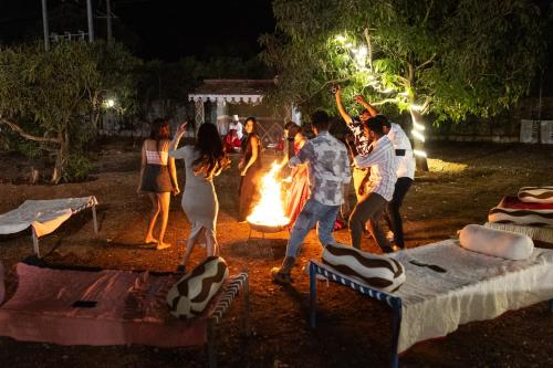 a group of people dancing around a fire at night at Daksh Eden Greenz -A Luxury Resort in Sasan Gir in Sasan Gir