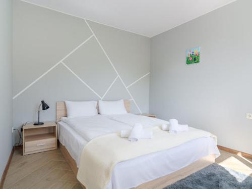 a white bedroom with a bed and a night stand at Къща "Конакъ" in Kyustendil