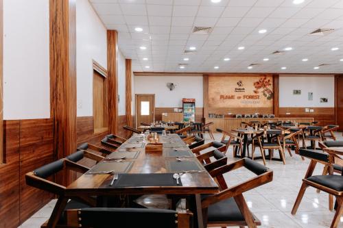 a large dining room with wooden tables and chairs at Daksh Eden Greenz -A Luxury Resort in Sasan Gir in Sasan Gir
