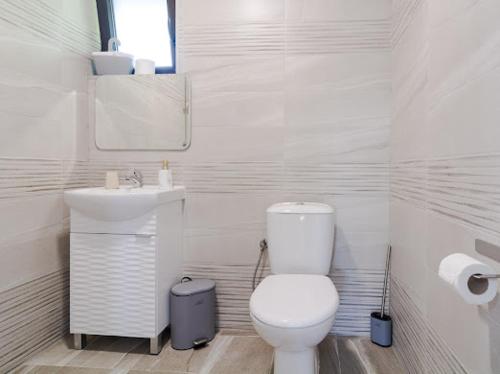 a white bathroom with a toilet and a sink at Къща "Конакъ" in Kyustendil