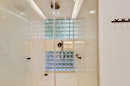 a glass shower in a white bathroom with a window at New 3 BR Jungle Villa in gated community in Blahbatu