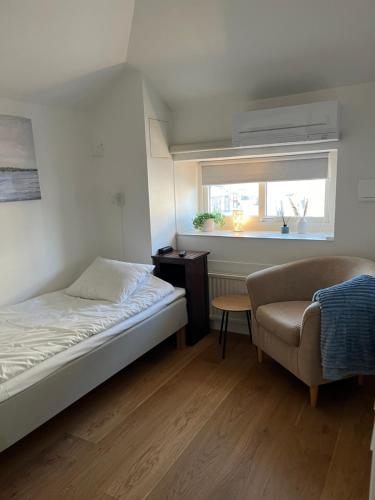 een slaapkamer met een bed, een stoel en een raam bij Drottninggatans Vandrarhem in Karlskrona