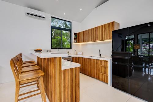a kitchen with wooden cabinets and a black refrigerator at New 3 BR Jungle Villa in gated community in Blahbatu