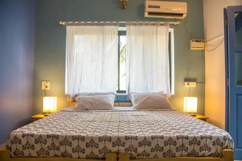 a bedroom with a large bed with two windows at Coco Moon Morjim in Morjim