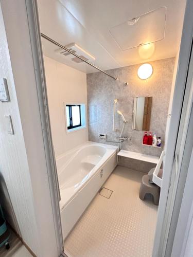 a white bathroom with a tub and a sink at The Ritz Okinawa Kise 2-Free parking for 2 cars, 3LDK, 2 bathrooms in Nago