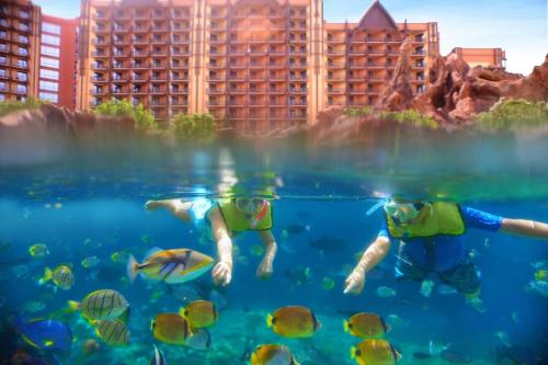 two people swimming in the water at the disney resort at Aulani, Disney Vacation Club Villas in Kapolei