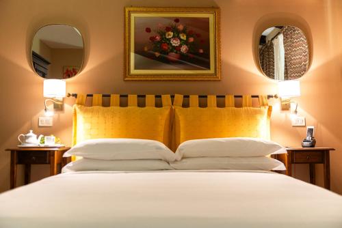a bedroom with a white bed with two mirrors at Ghiaccio Bosco in Capalbio