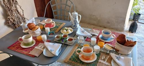 ein Tisch mit Tassen und Teller mit Essen drauf in der Unterkunft Une Nuit au Village - chambre d'hôtes de charme in Orgnac-lʼAven