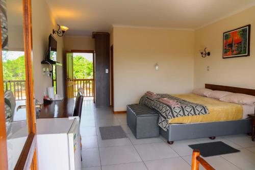 1 dormitorio con cama, escritorio y balcón en Riverview Inn en Malelane