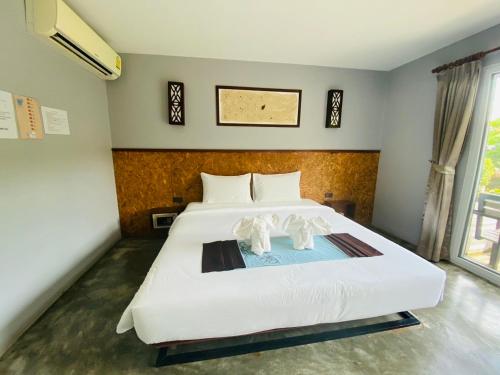 um quarto com uma grande cama branca com duas estatuetas em The Hip Resort @ Phi Phi em Phi Phi Don