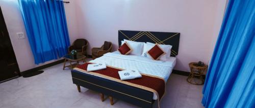 a bedroom with a large bed with blue curtains at Kuttralam Resorts in Kuttālam