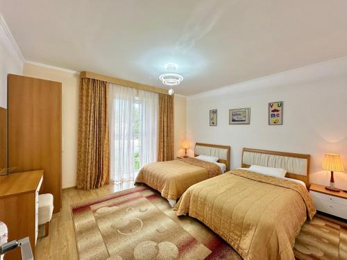 een hotelkamer met 2 bedden en een televisie bij Raduga West 'Emerald' Cottage in Koshkolʼ