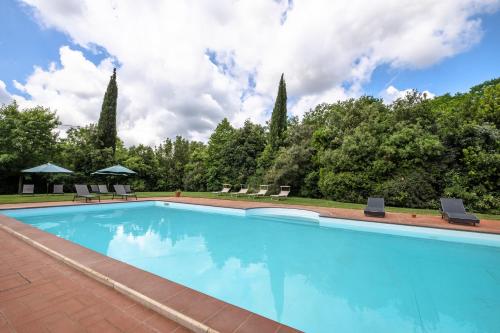 a swimming pool with chairs and trees in the background at Rosaspina - Appartamento 4 in Capalbio