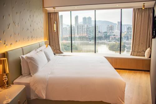 a bedroom with a white bed and a large window at YOHO Treasure Island Hotel in Macau