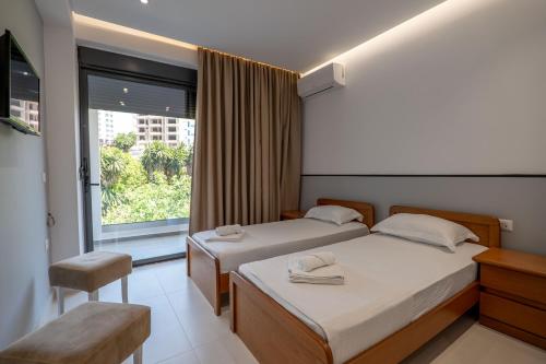 a hotel room with two beds and a window at Hotel Emblem in Sarandë