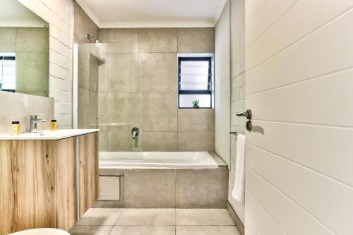 a bathroom with a tub and a sink at WINK Aparthotel Eaton Square in Cape Town