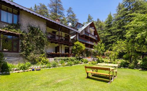 a bench sitting in the grass in front of a building at Bedzzz Xclusiv Baikunth, Manali By Leisure Hotels - 650 meters from Hidimba Devi Temple in Manāli