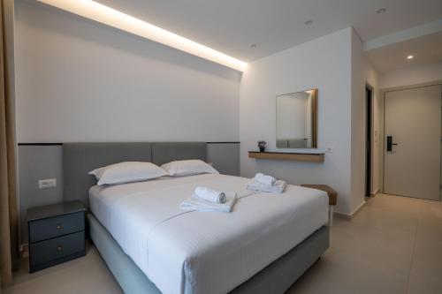 a bedroom with a large white bed with towels on it at Hotel Emblem in Sarandë