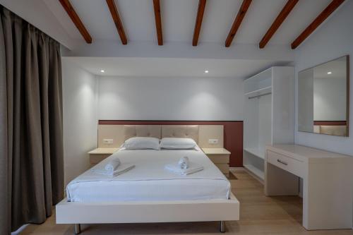a bedroom with a white bed and a mirror at Hotel Emblem in Sarandë