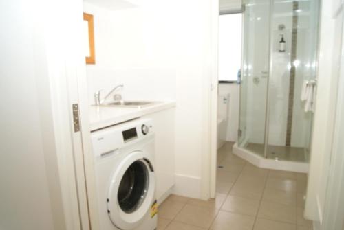 a white bathroom with a washing machine and a sink at Mill View Link in Albany