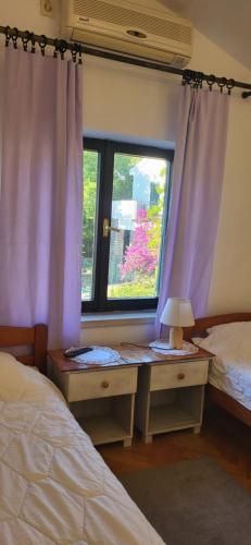 a bedroom with two beds and a window with purple curtains at Studio apartman in Meljine