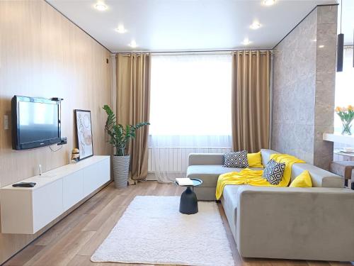 uma sala de estar com um sofá e uma televisão em Apartament Almaty Akvarel em Almaty