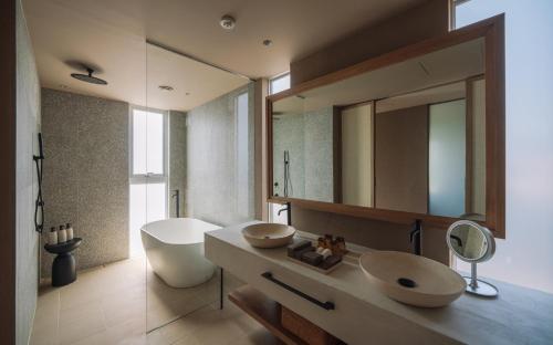 a bathroom with a sink and a mirror and a tub at アヤンナ宮古島 in Miyako Island