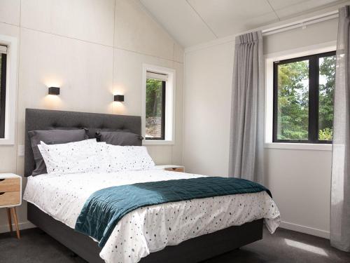 a bedroom with a large bed and two windows at Jacks Lodge Townhouse in Hanmer Springs