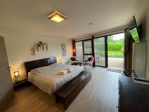a bedroom with a large bed and a large window at B&B Le Bouchat-Oreille in Spontin