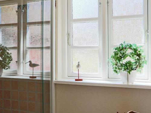 a bathroom window with two plants and a bird at 6 person holiday home in HISHULT in Knäred