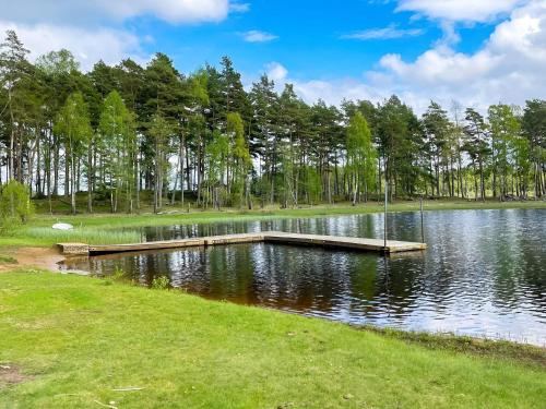 a dock on a lake with trees in the background at 6 person holiday home in HISHULT in Knäred