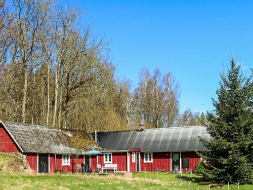 a red barn with a black roof and a tree at 6 person holiday home in HISHULT in Knäred