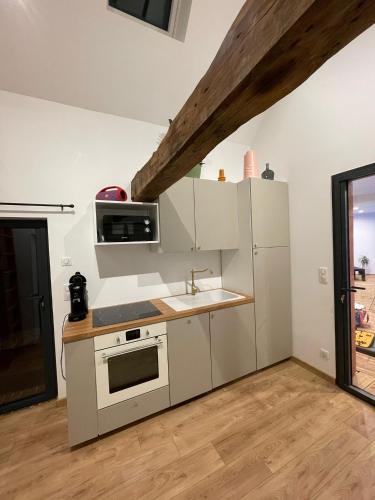 a kitchen with white appliances and a wooden floor at A l oree du bois piscine intérieure privée sans vis à vis in Auvilliers
