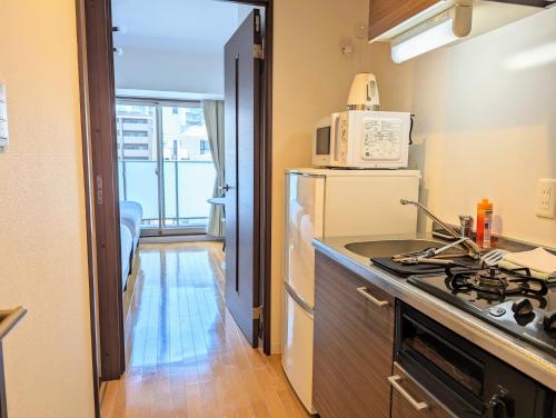 a small kitchen with a stove and a microwave at Home cruise Awaza in Osaka