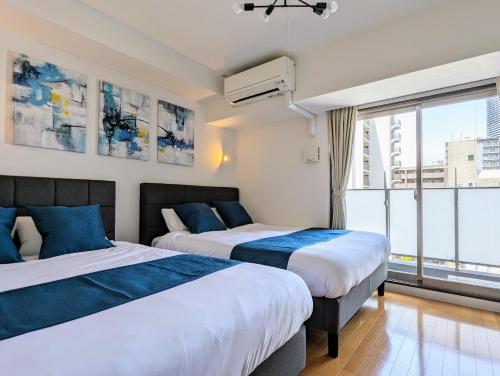 two beds in a room with a large window at Home cruise Awaza in Osaka
