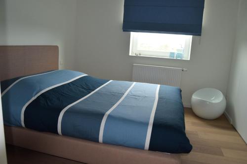 ニーウポールトにあるKarthuizer duinzichtのベッドルーム1室(青い掛け布団、窓付)