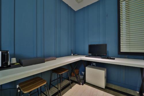 a blue room with a desk with a computer and two stools at Ignis Hotel busan sports complex branch in Busan