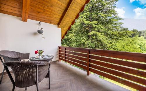 a balcony with a table and a view of a tree at Bedzzz Xclusiv Baikunth, Manali By Leisure Hotels - 650 meters from Hidimba Devi Temple in Manāli