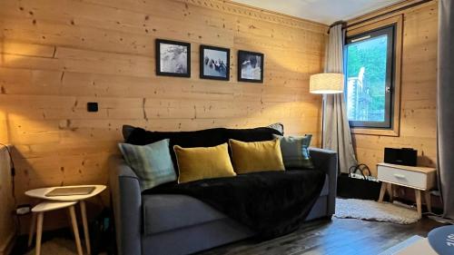 een woonkamer met een bank en houten wanden bij Le 41 du Lyret - Appartement type studio pour deux avec vue sur les Aiguilles dans Chamonix Centre in Chamonix-Mont-Blanc