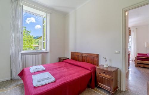 Schlafzimmer mit einem Bett mit roter Bettwäsche und einem Fenster in der Unterkunft 1 Bedroom Pet Friendly Apartment In Loco Di Rovegno in Torriglia
