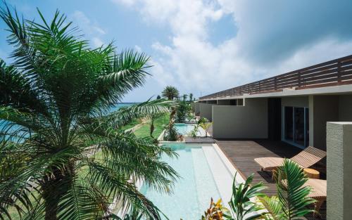 a house with a swimming pool and a palm tree at アヤンナ宮古島 in Miyako Island