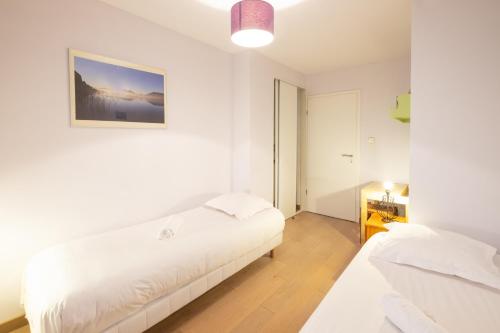 a white room with two beds and a picture on the wall at Printemps chaleureux T4 +2 place de parking privée in Annecy