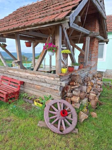 a wooden building with a wooden wheel and flowers at Apartmani Feliks in Resavica