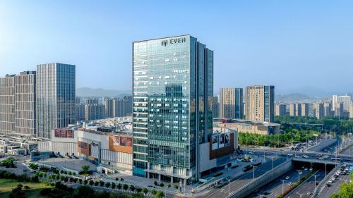 EVEN Hotel Qingdao Laoshan - an IHG Hotel في تشينغداو: مبنى زجاجي طويل في مدينة بها طريق سريع
