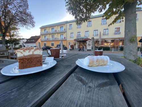 Simon - Hotel & Café في باد تاتزماندورف: قطعتين من الكعك جالسين على طاولة خشبية