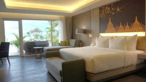 um quarto de hotel com uma cama grande e um sofá em Amaranta Prambanan Yogyakarta em Yogyakarta
