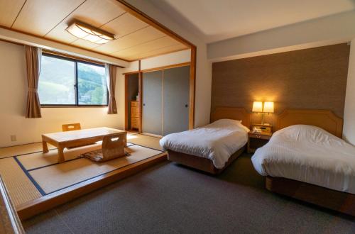 a hotel room with two beds and a table at Hakuba Panorama Hotel in Hakuba