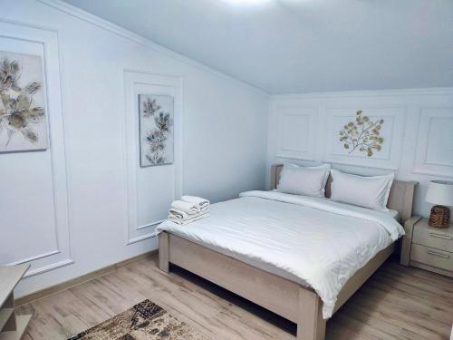 a white bedroom with a large bed with white sheets at Pensiunea Sub Horiță in Leordina