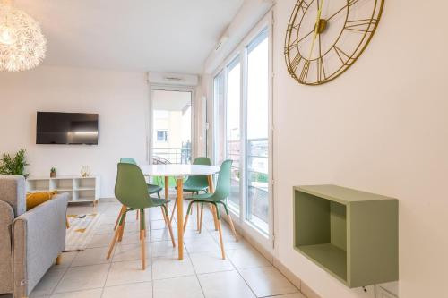ein Wohnzimmer mit einem Tisch, Stühlen und einer Uhr in der Unterkunft Superbe T2 gare Annemasse avec Garage et balcon in Ville-la-Grand